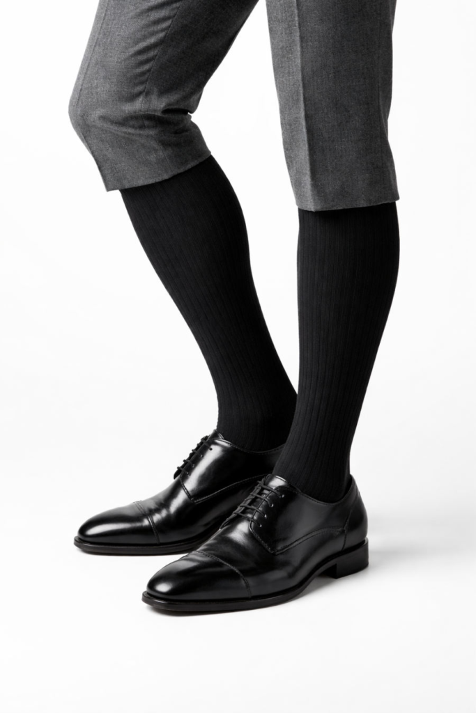 Hombre usando calcetín ejecutivo Ingesa negro opaco con zapatos de vestir negros y pantalón gris
